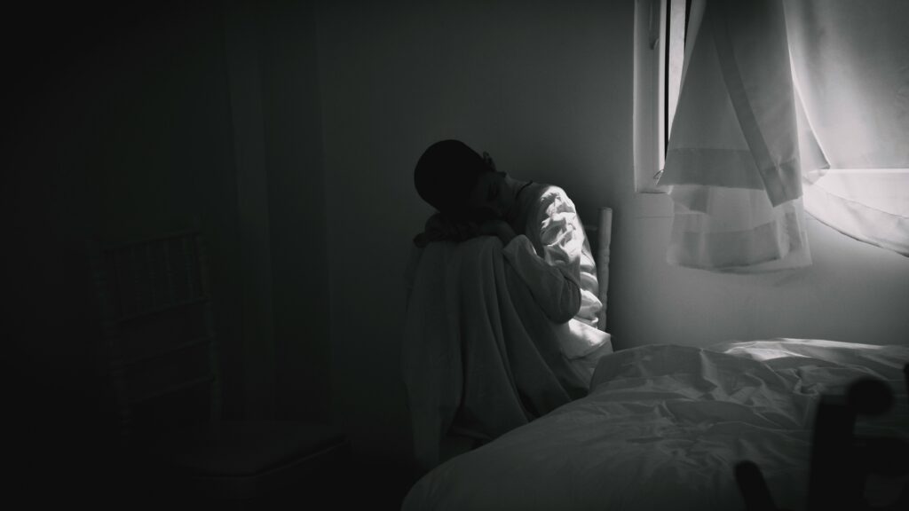Girl sitting alone in a room: loneliness has an outsized impact on both physical and mental health. How can you cope if you are experiencing loneliness?